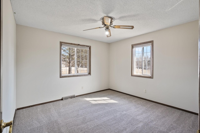 carpeted spare room featuring visible vents, baseboards, a textured ceiling, and a ceiling fan