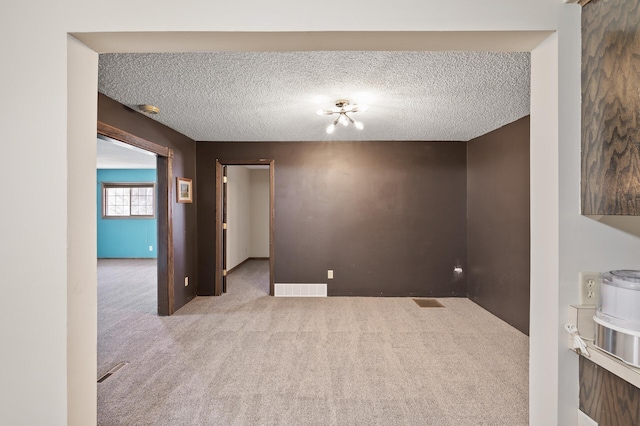 spare room with visible vents, carpet floors, and a textured ceiling