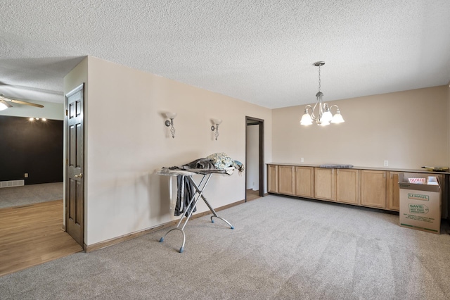 unfurnished dining area featuring visible vents, light colored carpet, and a textured ceiling