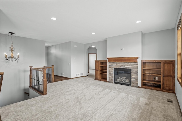 unfurnished living room with arched walkways, a notable chandelier, carpet, and visible vents