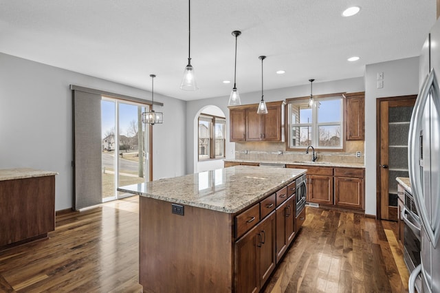 kitchen featuring a center island, freestanding refrigerator, arched walkways, and dark wood finished floors