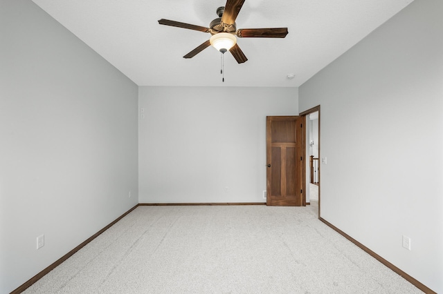 empty room with carpet flooring, baseboards, and a ceiling fan