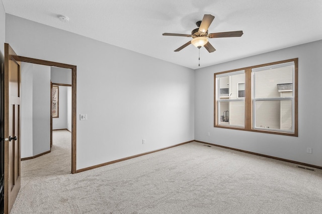 unfurnished room with visible vents, ceiling fan, light carpet, and baseboards