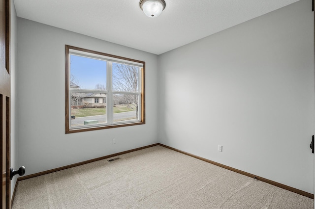 carpeted spare room with visible vents and baseboards