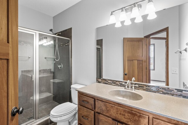 full bathroom with a shower stall, tasteful backsplash, vanity, and toilet