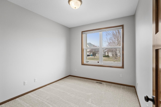 carpeted empty room featuring baseboards and visible vents