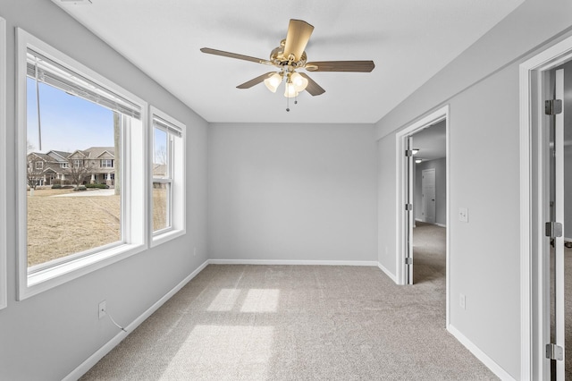 carpeted spare room with baseboards and a ceiling fan