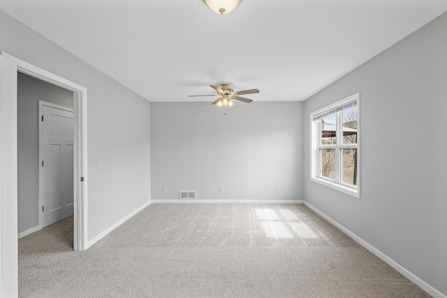 spare room featuring visible vents, baseboards, a ceiling fan, and light carpet