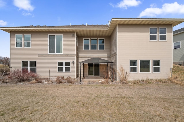rear view of house with a patio and a lawn