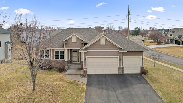 view of front of home featuring roof with shingles, driveway, an attached garage, a front yard, and brick siding