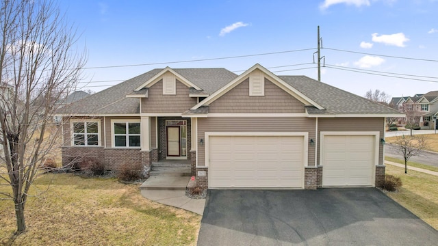 view of front facade with a shingled roof, an attached garage, brick siding, a front lawn, and driveway