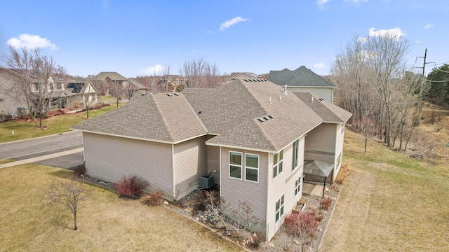 view of property exterior with a yard, a residential view, cooling unit, and a shingled roof
