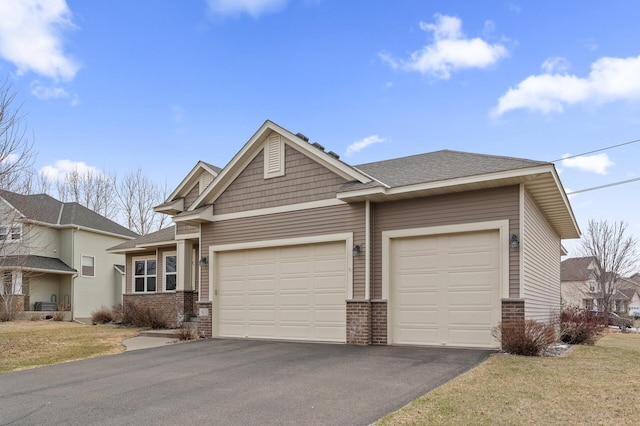 view of front of property with a shingled roof, aphalt driveway, brick siding, and an attached garage