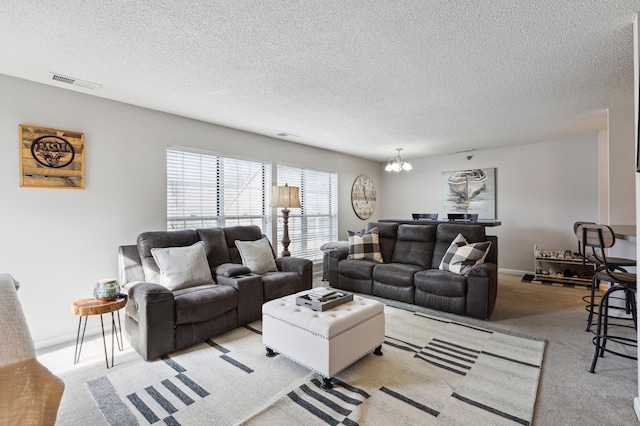 living area featuring visible vents, baseboards, a chandelier, light colored carpet, and a textured ceiling