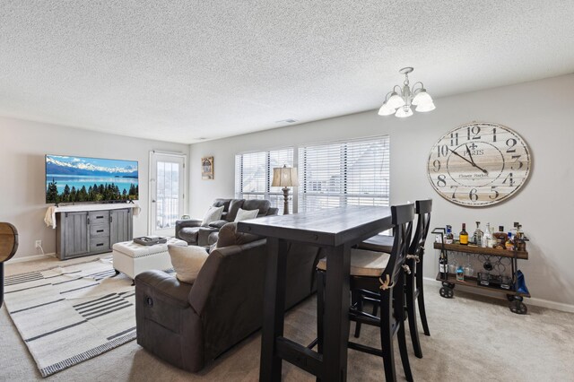 living room with an inviting chandelier, light colored carpet, baseboards, and a textured ceiling