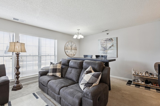 living area featuring visible vents, light carpet, baseboards, and a chandelier