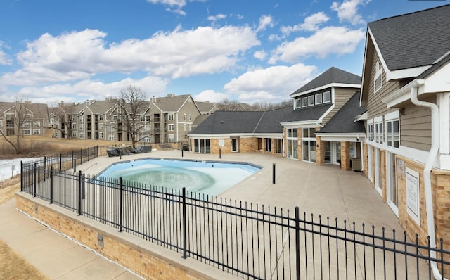 community pool featuring a patio, fence, and a residential view