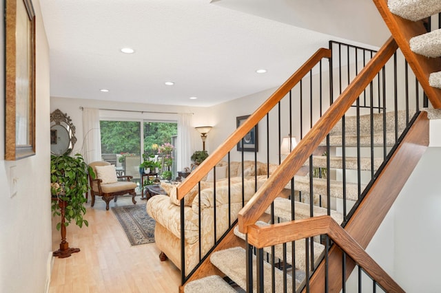 staircase featuring wood finished floors and recessed lighting