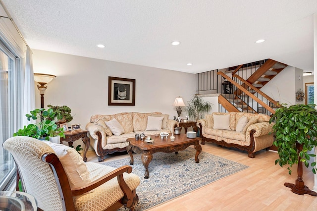 living area with a textured ceiling, stairs, wood finished floors, and recessed lighting