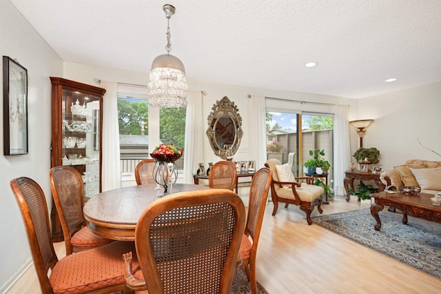 dining space with light wood-style floors, recessed lighting, a notable chandelier, and a textured ceiling