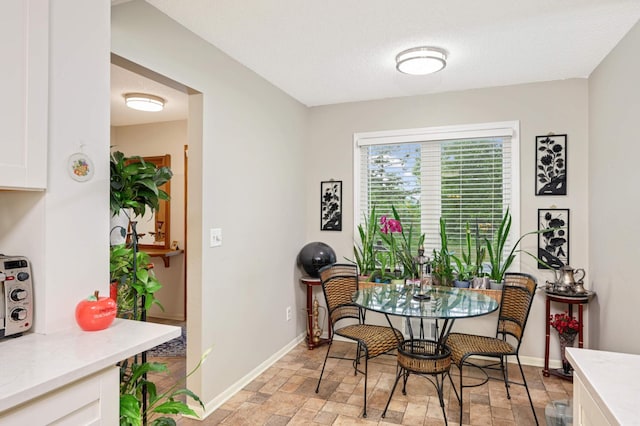 dining room featuring baseboards, stone finish floor, and a textured ceiling