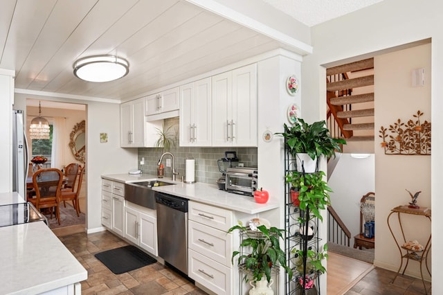 kitchen featuring tasteful backsplash, dishwasher, freestanding refrigerator, white cabinetry, and a sink