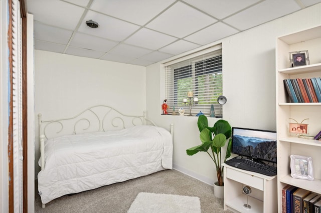 carpeted bedroom featuring a paneled ceiling and baseboards