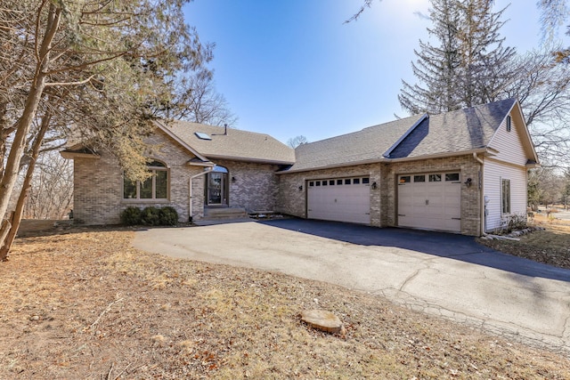 single story home featuring driveway, brick siding, and roof with shingles