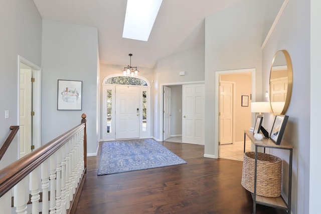 foyer with lofted ceiling with skylight, wood finished floors, and baseboards