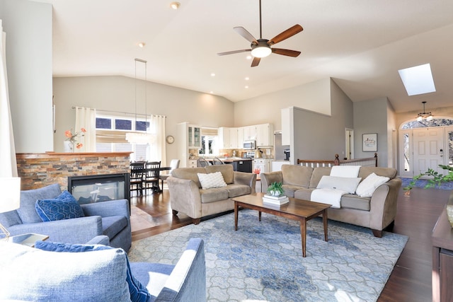 living area featuring dark wood finished floors, high vaulted ceiling, a skylight, and ceiling fan