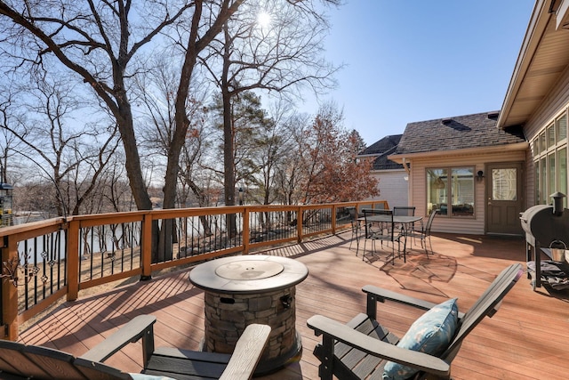 deck featuring outdoor dining space and an outdoor fire pit