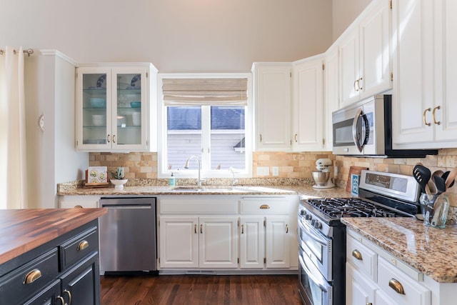 kitchen featuring a sink, stainless steel appliances, white cabinets, glass insert cabinets, and wooden counters