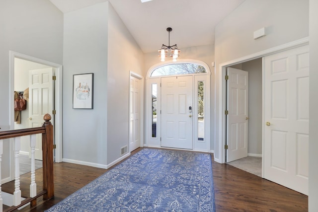 foyer entrance with dark wood-style floors, visible vents, a chandelier, and baseboards