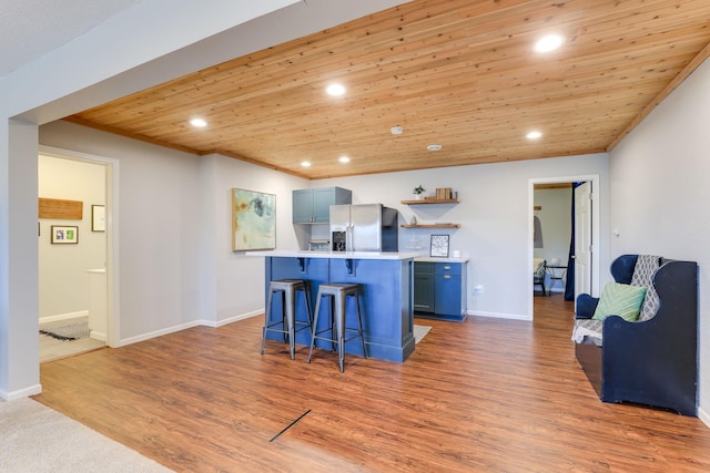 kitchen with wood ceiling, a kitchen bar, light countertops, recessed lighting, and stainless steel refrigerator with ice dispenser