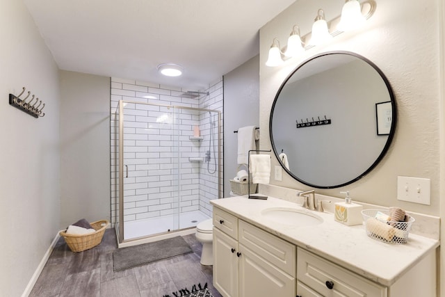 bathroom featuring toilet, a stall shower, wood finished floors, baseboards, and vanity