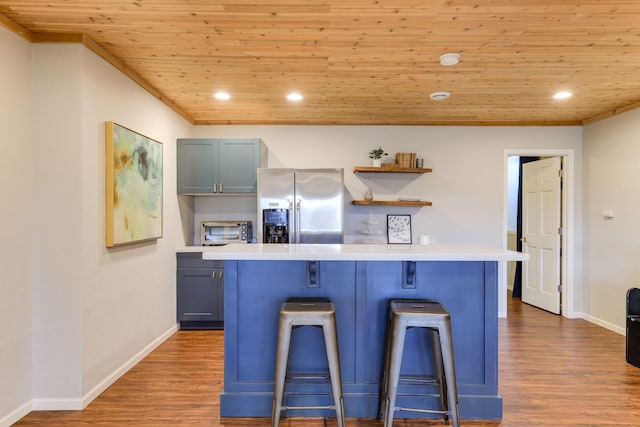 kitchen with stainless steel fridge with ice dispenser, a breakfast bar area, light countertops, wooden ceiling, and wood finished floors