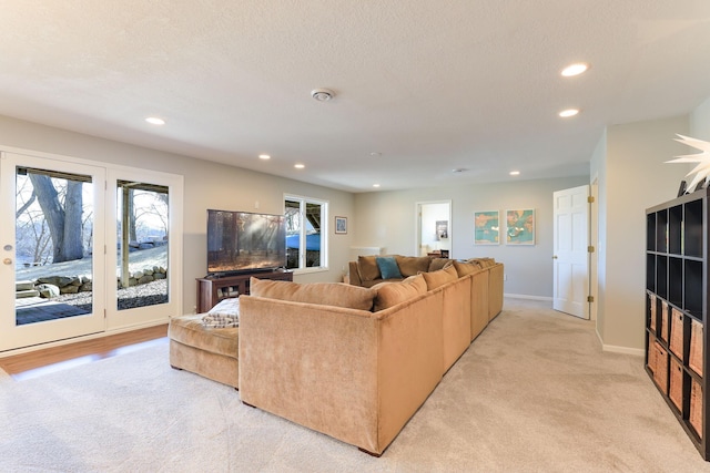 living area featuring recessed lighting, a textured ceiling, light colored carpet, and baseboards