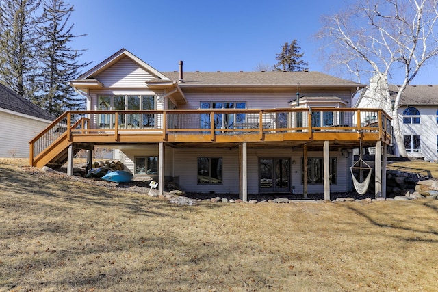 rear view of house featuring a lawn, a deck, and stairs