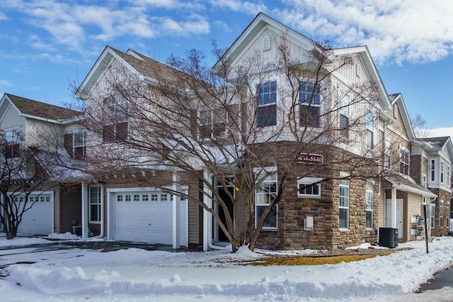 view of front facade with a garage, stone siding, and central AC unit