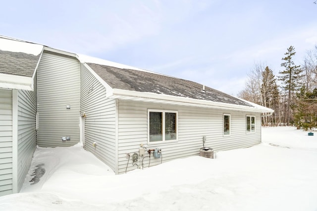 snow covered back of property with a shingled roof