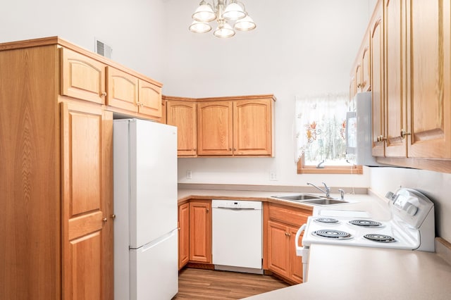 kitchen featuring light wood finished floors, light countertops, visible vents, a sink, and white appliances