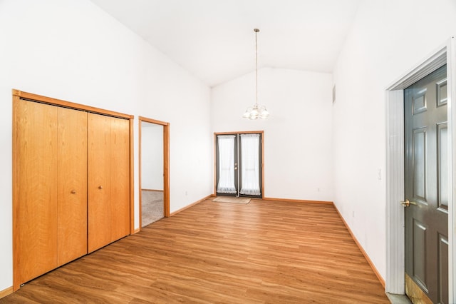 interior space with high vaulted ceiling, baseboards, light wood finished floors, and an inviting chandelier