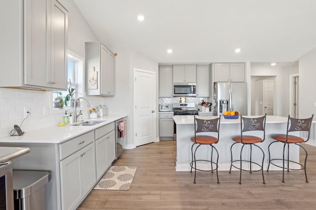 12273 71st Ct NE, Otsego, MN 55330 - kitchen with stainless steel appliances, a sink, a breakfast bar, backsplash, and gray cabinets