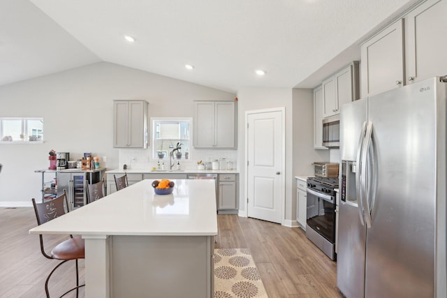 12273 71st Ct NE, Otsego, MN 55330 - kitchen with appliances with stainless steel finishes, gray cabinets, a sink, a breakfast bar area, and light wood-type flooring