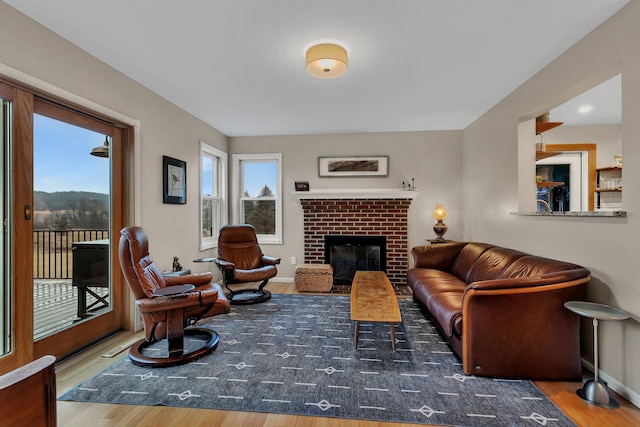 living room with a brick fireplace, baseboards, and wood finished floors