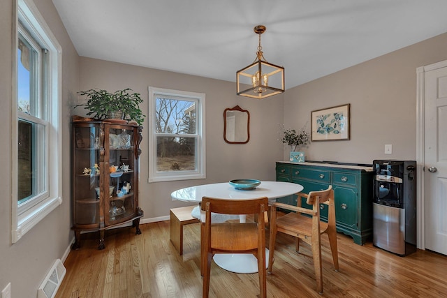 dining room featuring light wood-style floors, baseboards, visible vents, and an inviting chandelier