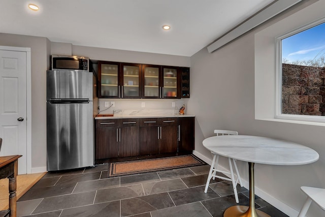 kitchen with stainless steel appliances, baseboards, dark brown cabinets, light countertops, and glass insert cabinets