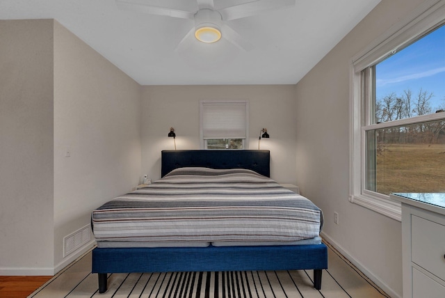 bedroom featuring light wood finished floors, baseboards, visible vents, and a ceiling fan