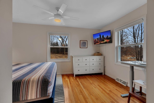 bedroom featuring light wood-type flooring, visible vents, multiple windows, and baseboards