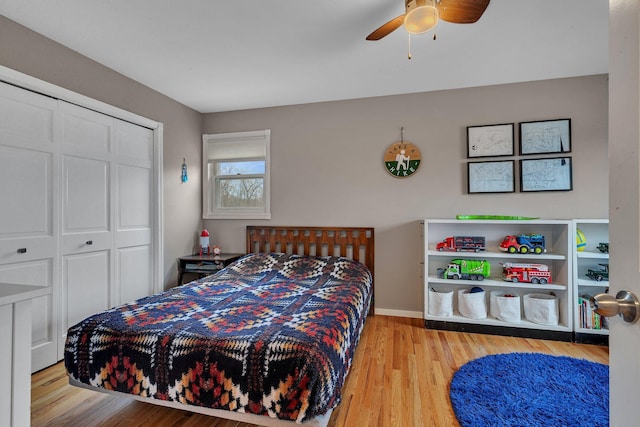 bedroom featuring a ceiling fan, a closet, baseboards, and wood finished floors